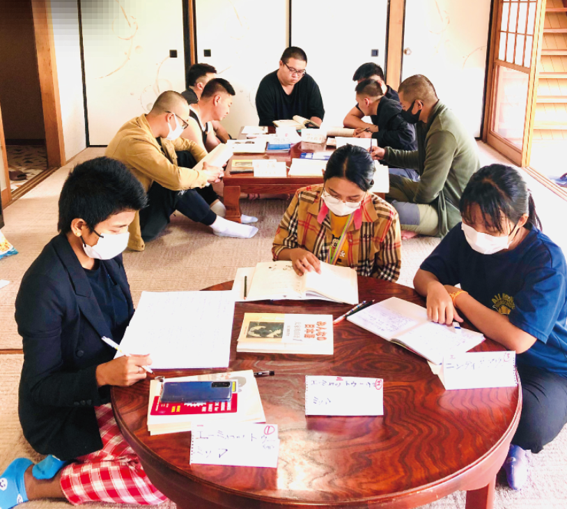 ちゃぶ台を囲んで日本語を勉強する外国籍の男女10人