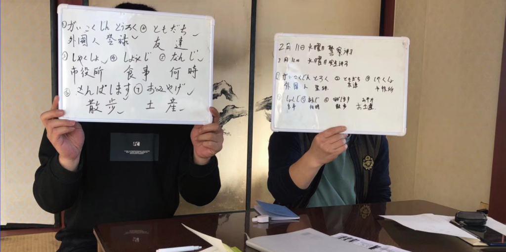 日本語を書いたボードを見せる2人